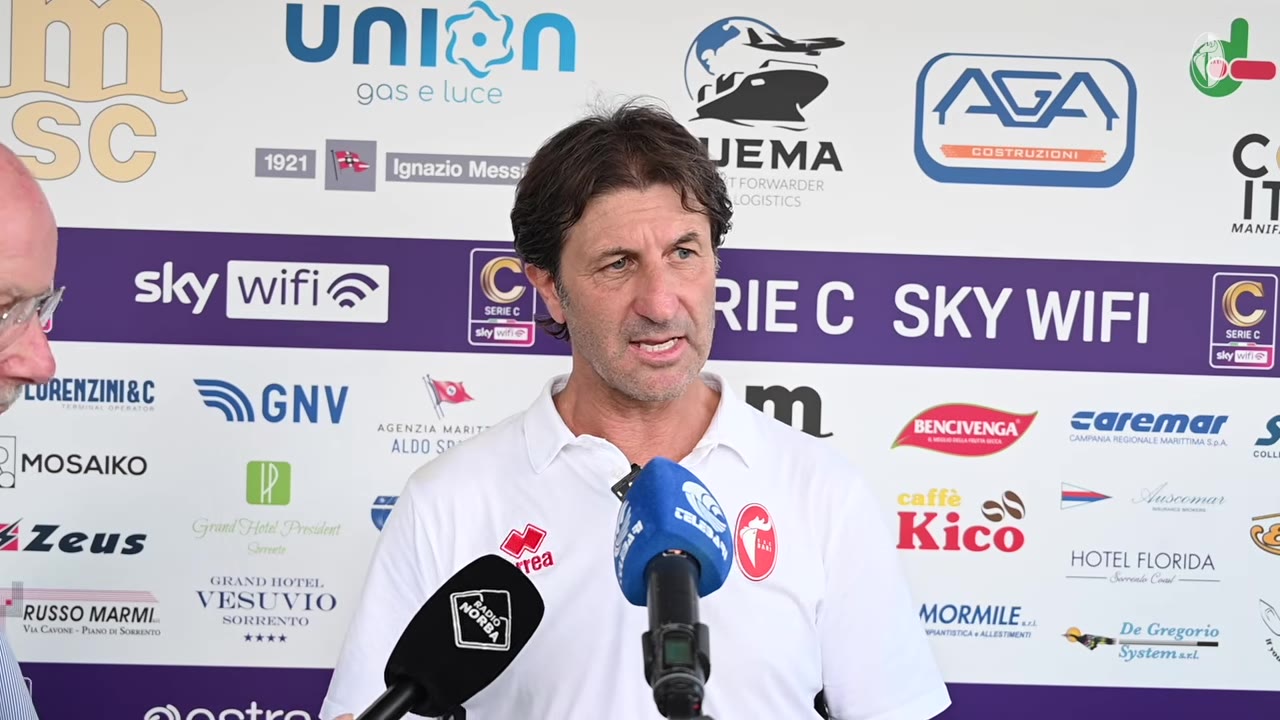 Allenatore parla davanti a backdrop sponsor