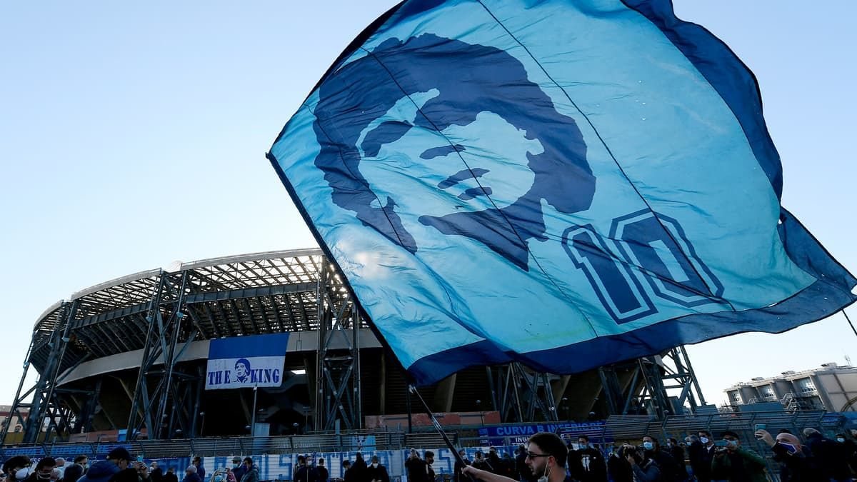 Tifosi del Napoli in curva con una bandiera dedicata a Diego Armando Maradona, simbolo del